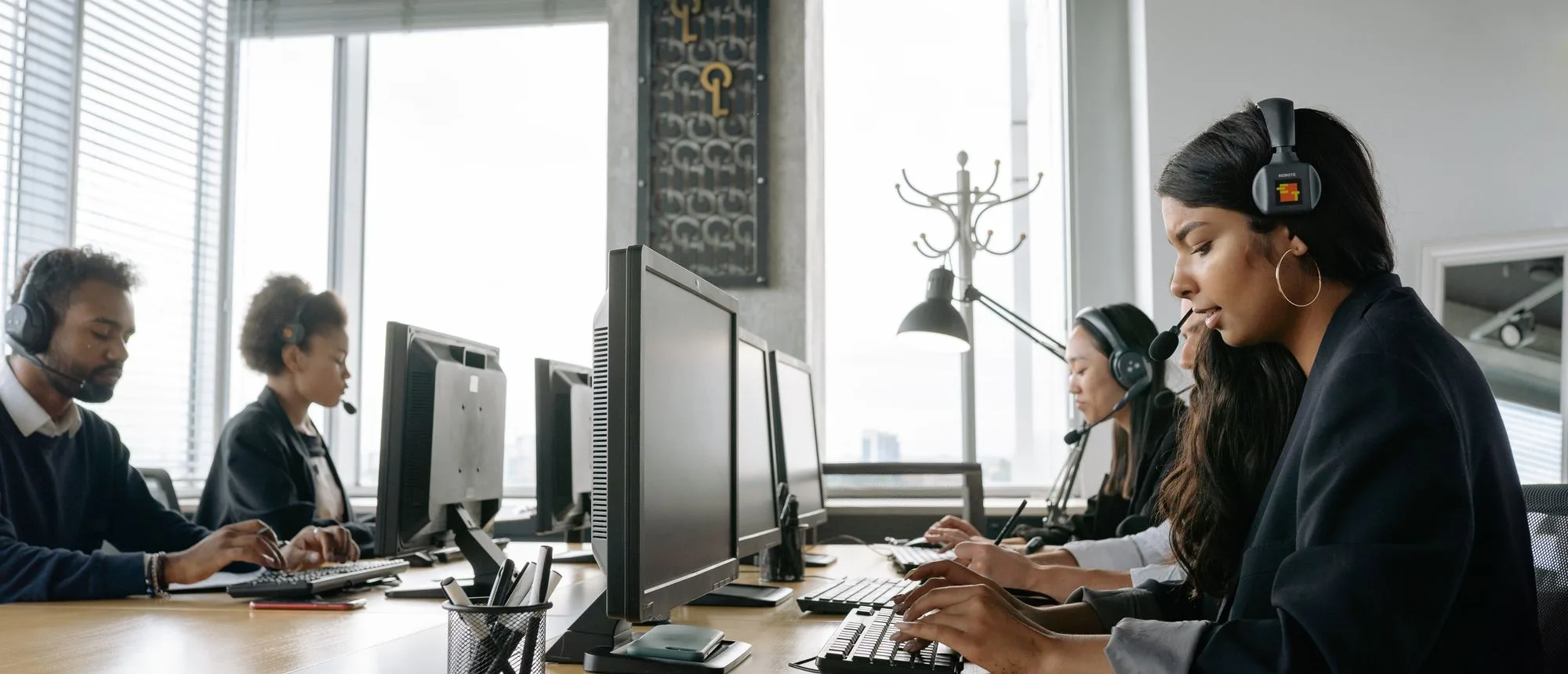 A call centre team wearing headsets handling calls at a row of monitors